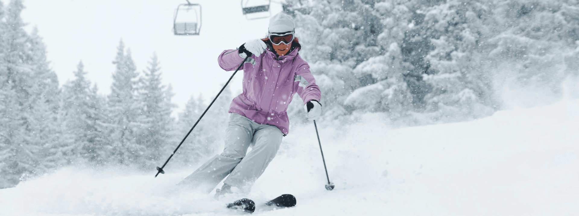 A skier in a pink jacket gracefully navigates a snowy slope.